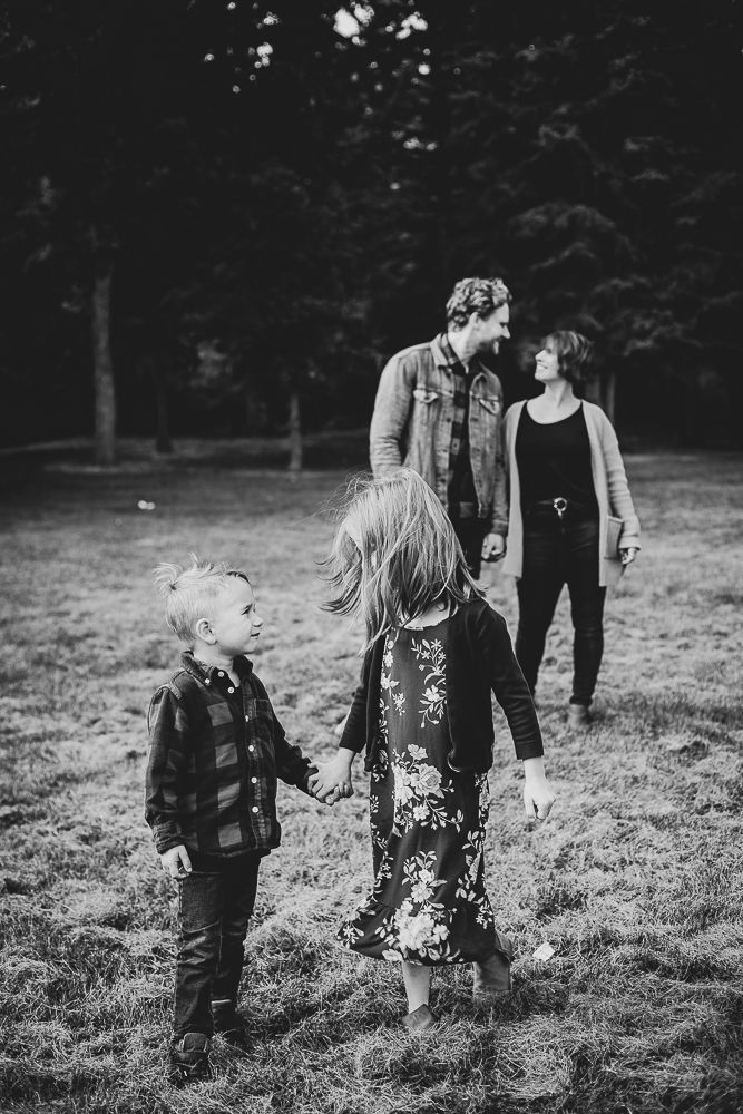 A black and white photo of a family holding hands in a field.