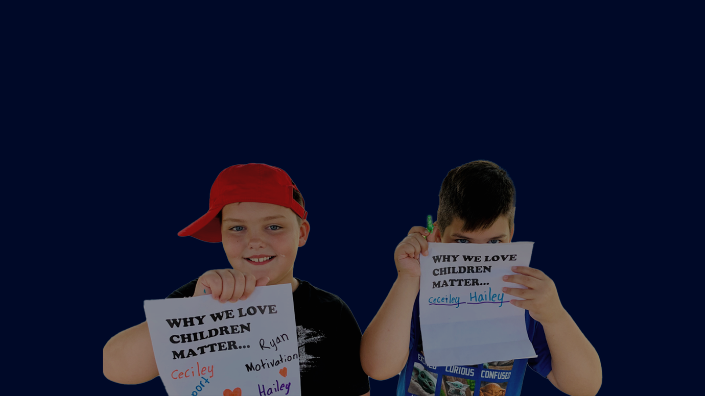 Two boys holding the signs they made that say why they love Children Matter.