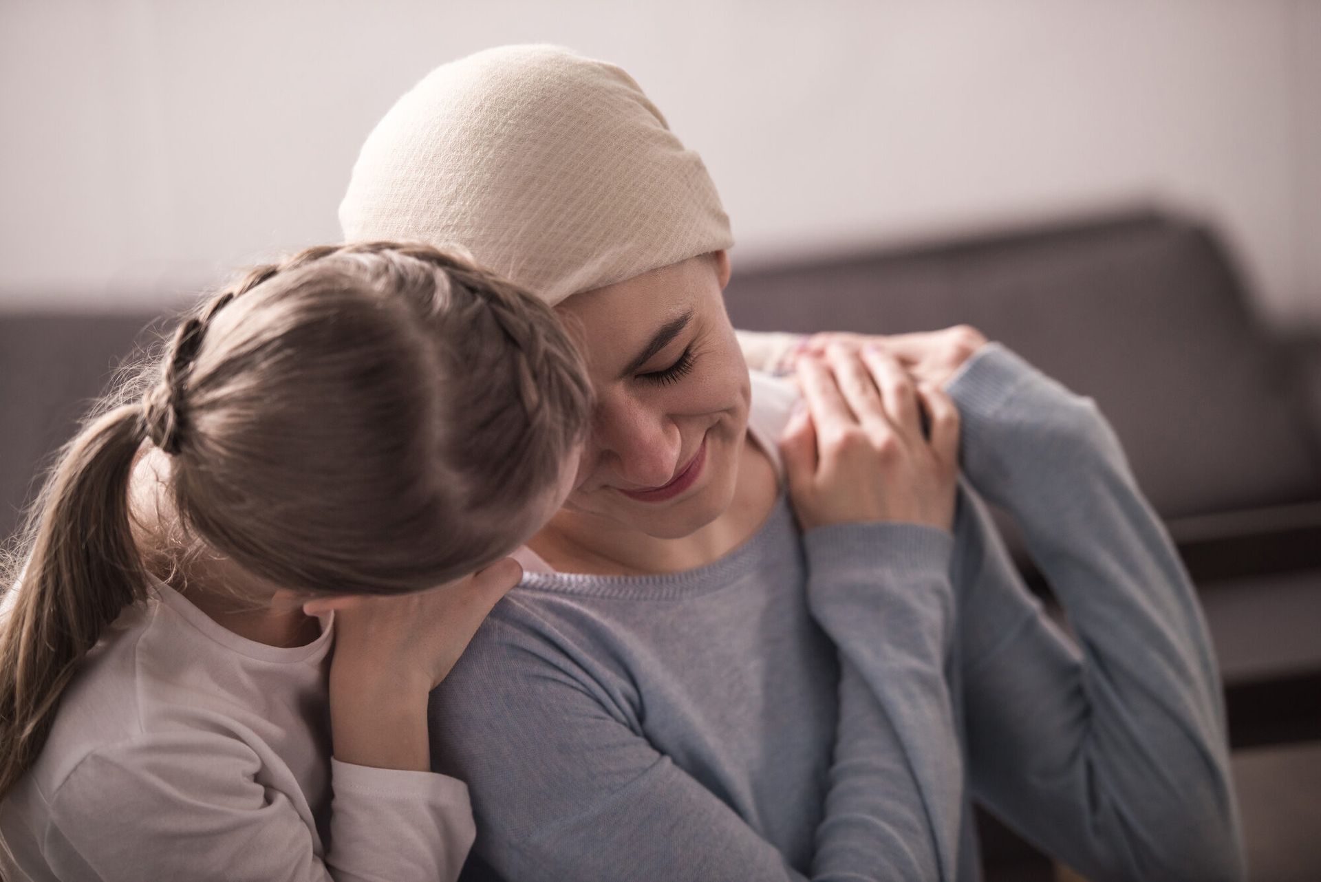 a little girl is hugging a woman with cancer .