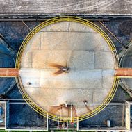 An aerial view of a large tank with a yellow fence around it.