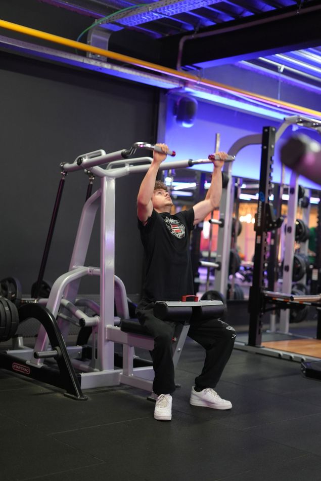 een sportschool vol met veel fitnessapparatuur en paarse lichten.