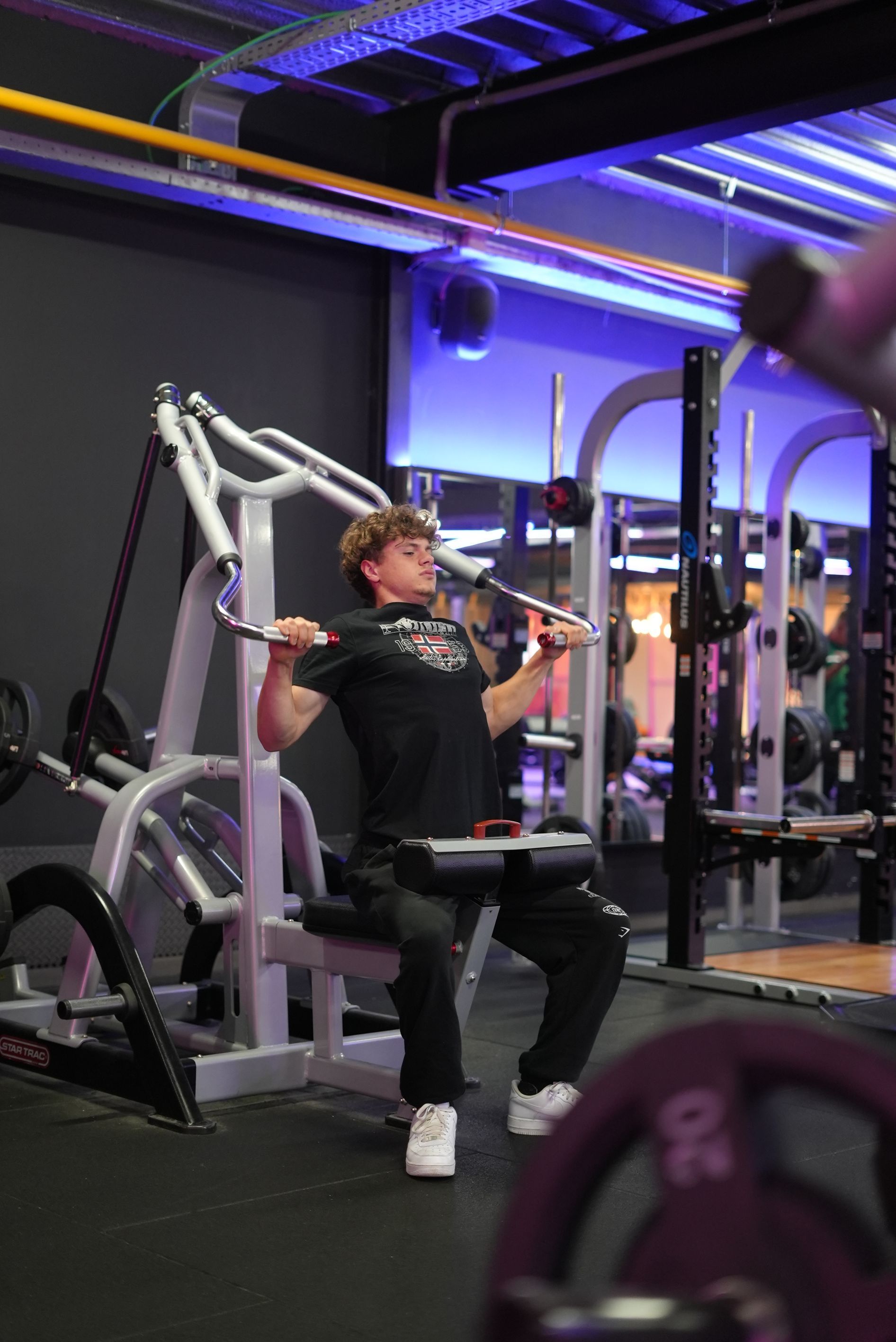 Een man zit op een apparaat in een sportschool.