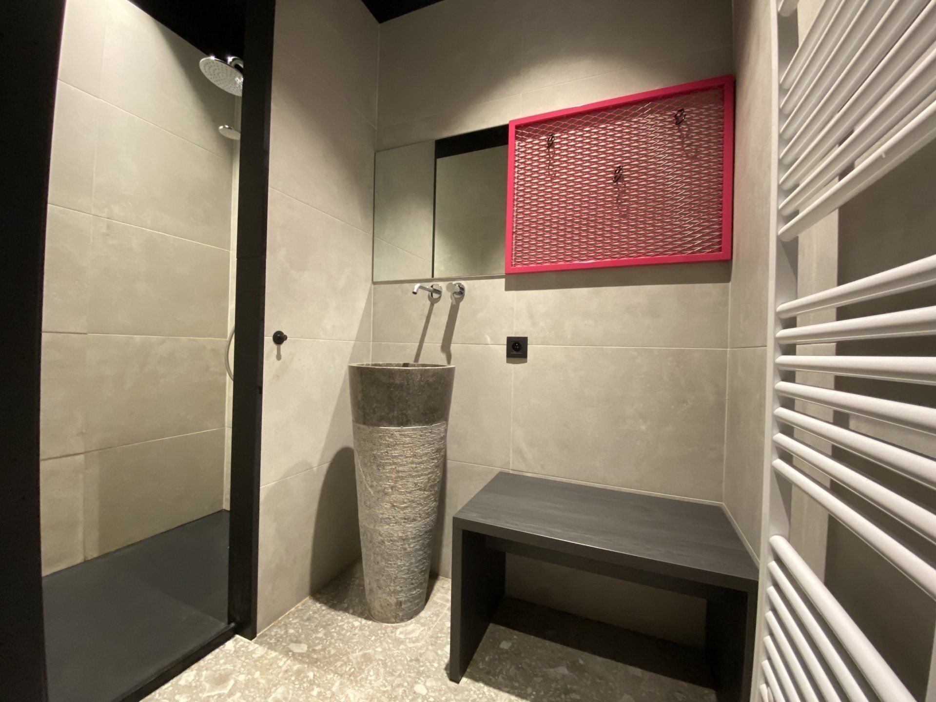 Een badkamer met wastafel, spiegel en bankje.