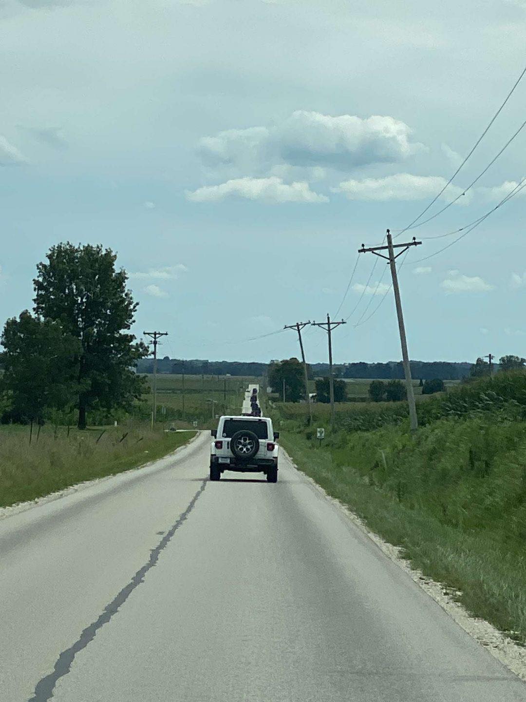 A white suv is driving down a country road