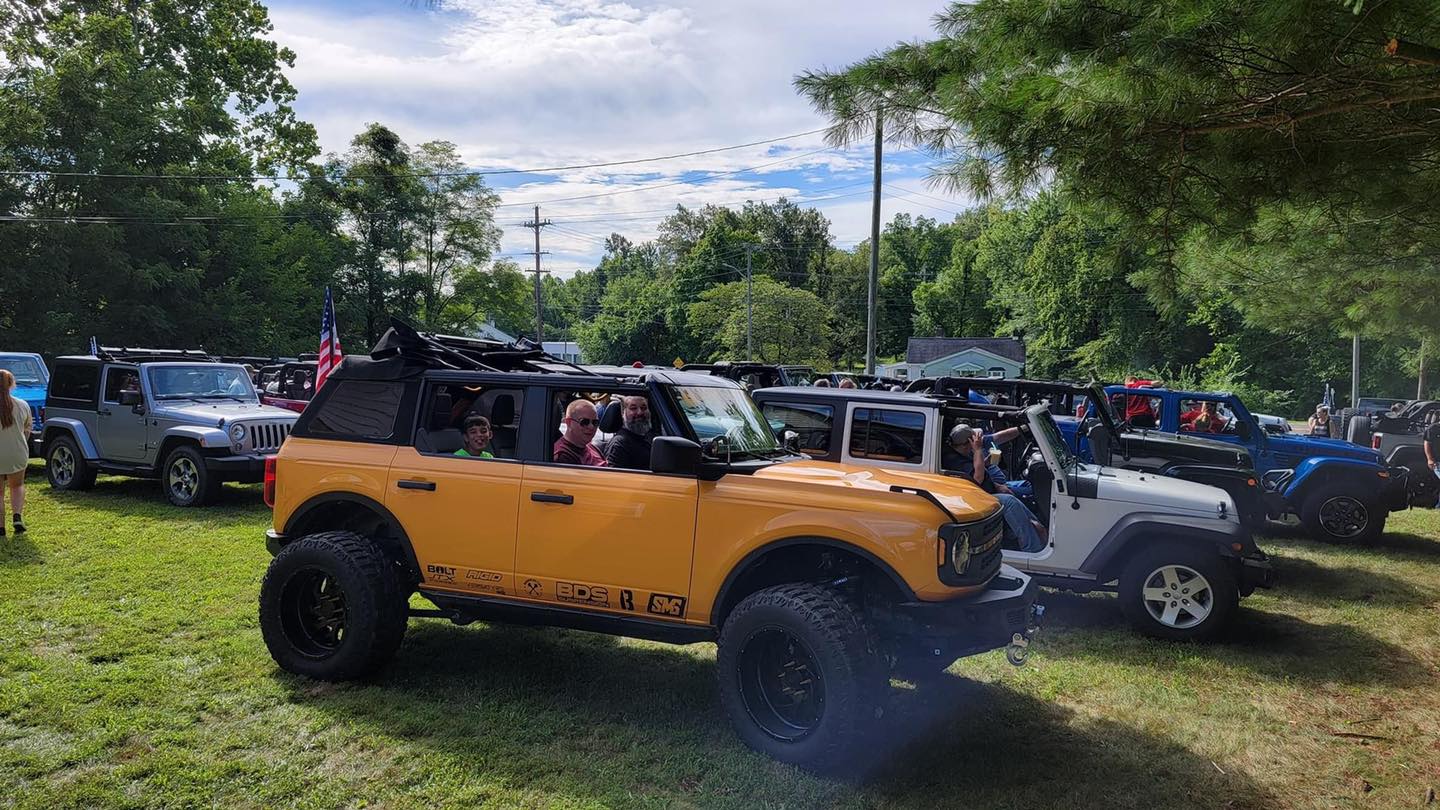 A row of jeep 's are parked in a grassy field.