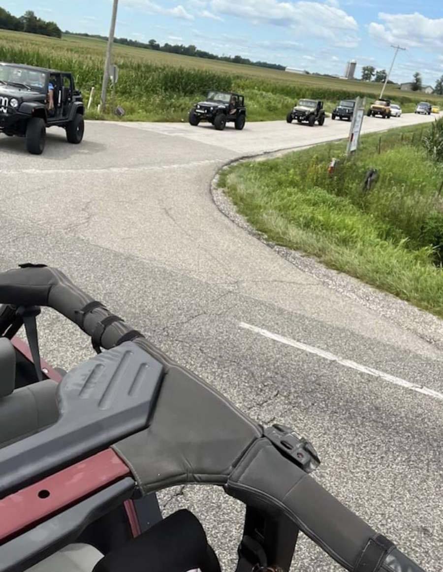 A group of jeep 's are driving down a road.