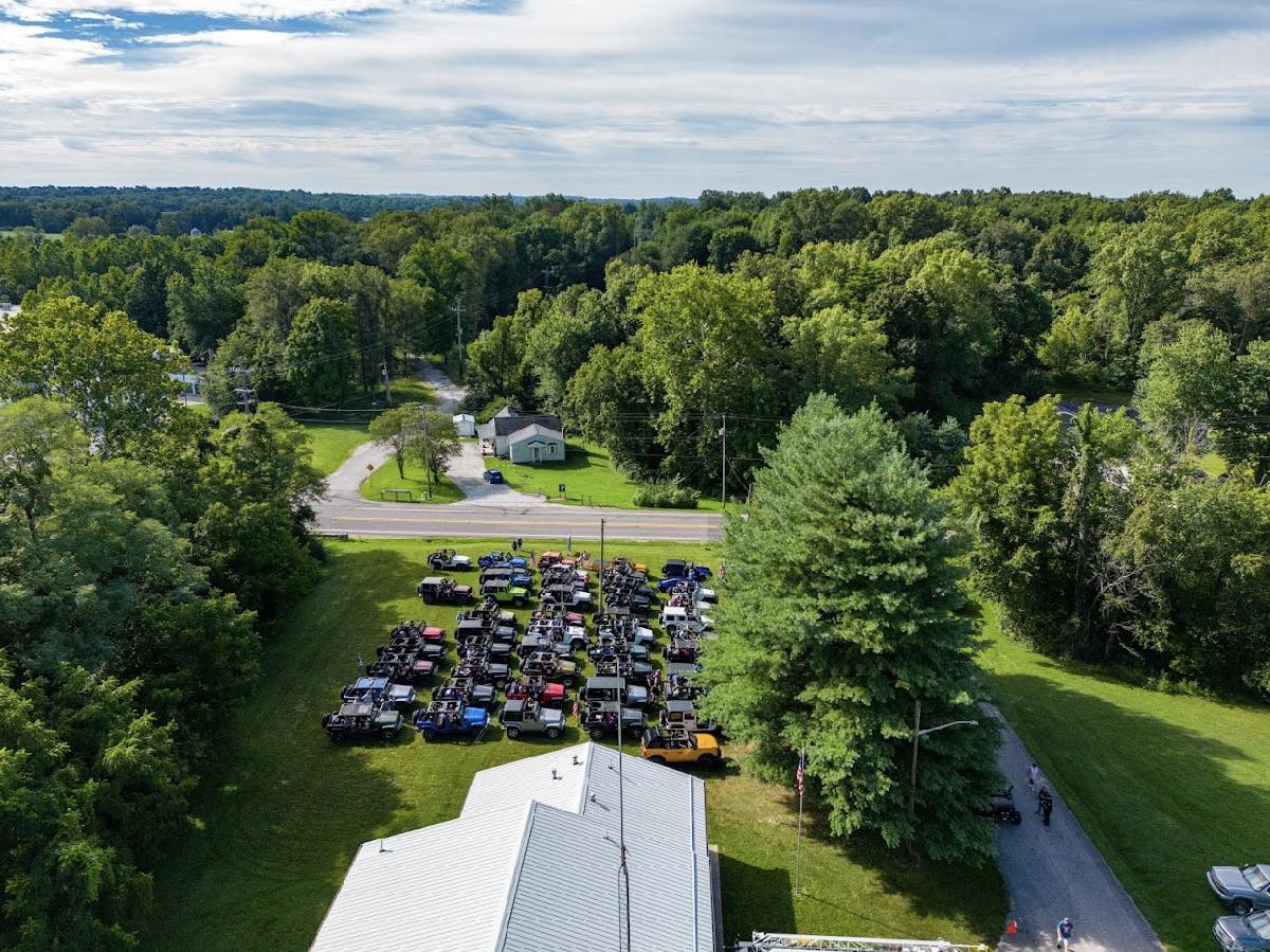 An aerial view of a parking lot filled with cars surrounded by trees.