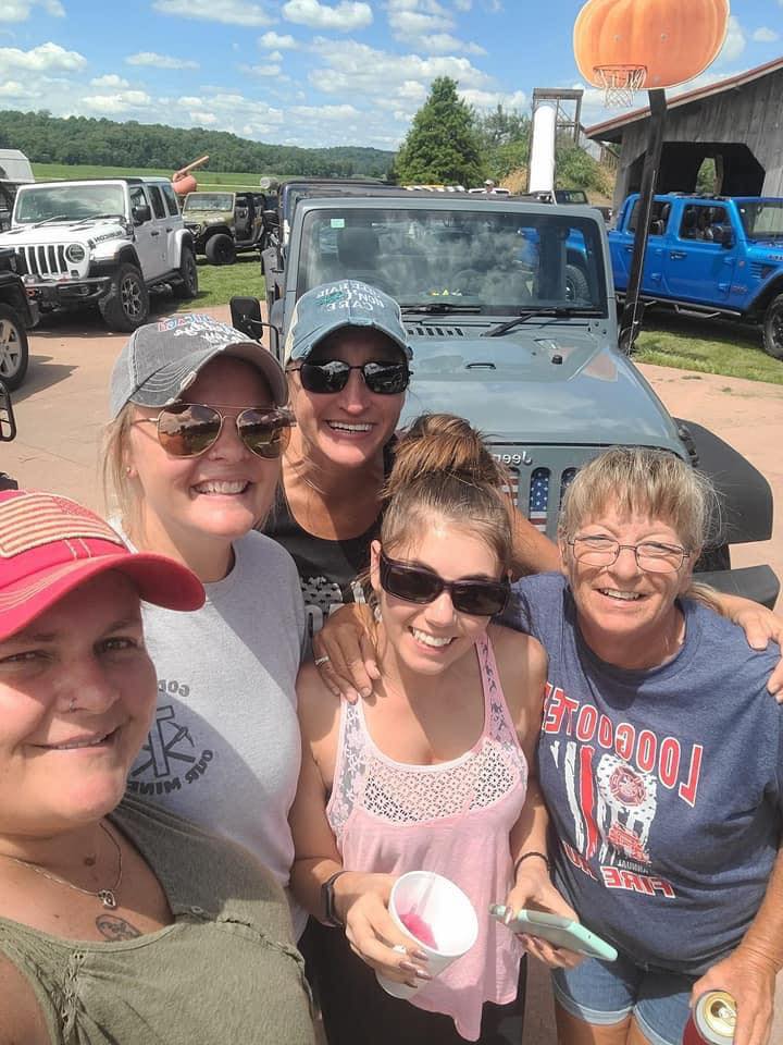 A group of women are posing for a picture in front of a jeep.