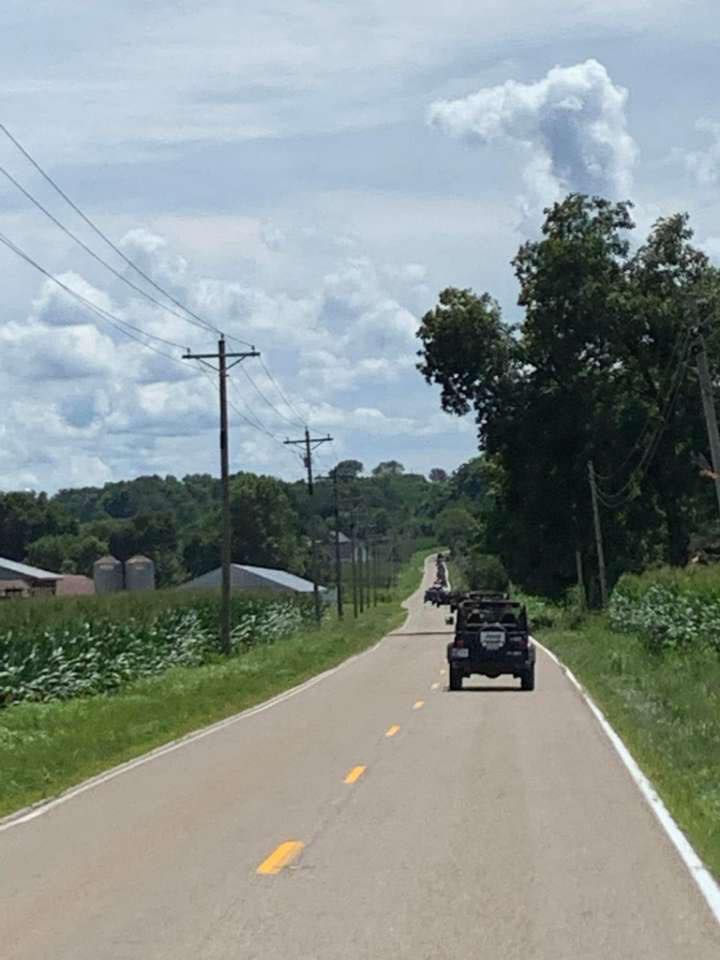 A black jeep is driving down a country road.