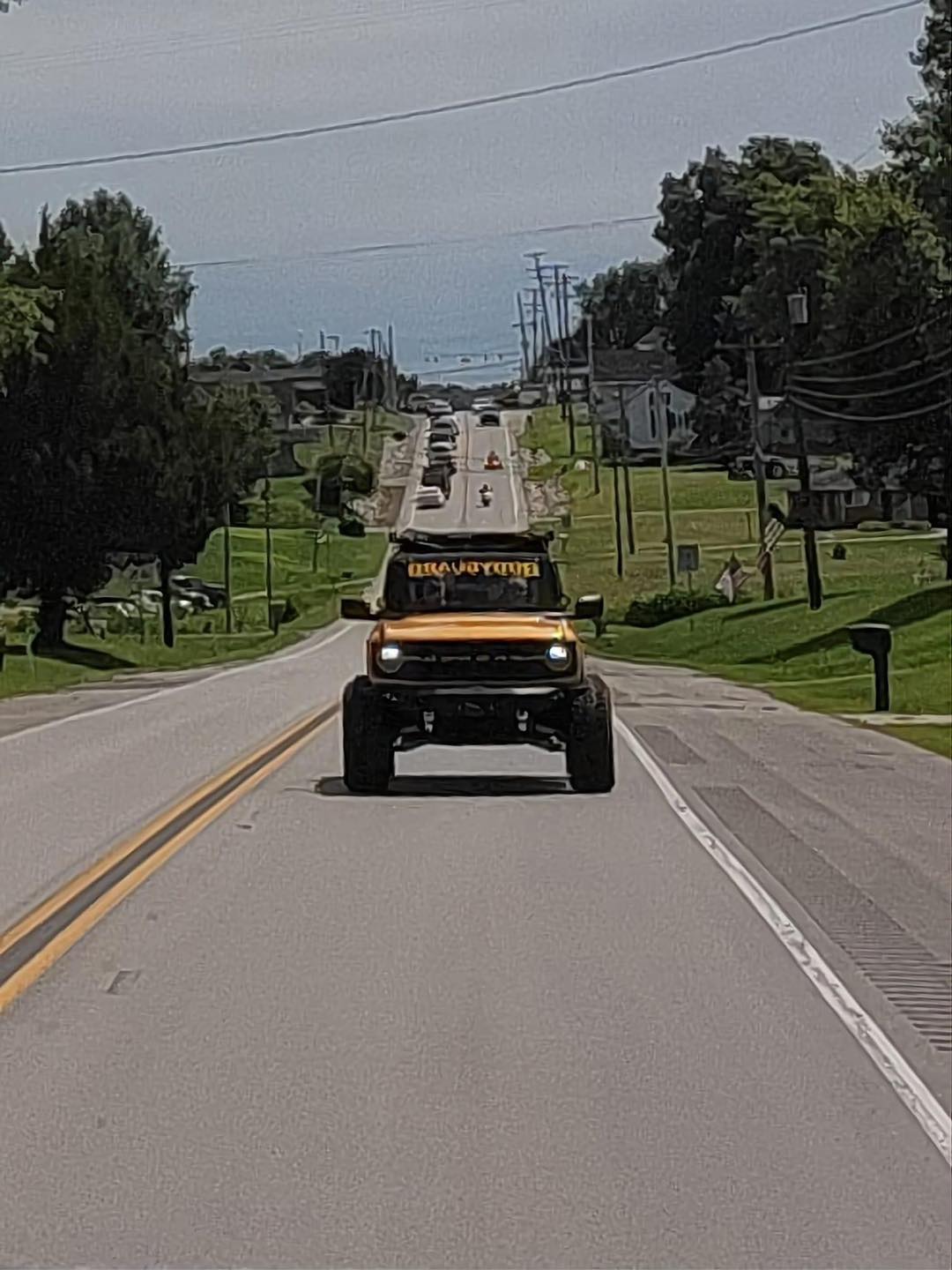 A yellow truck is driving down a road.