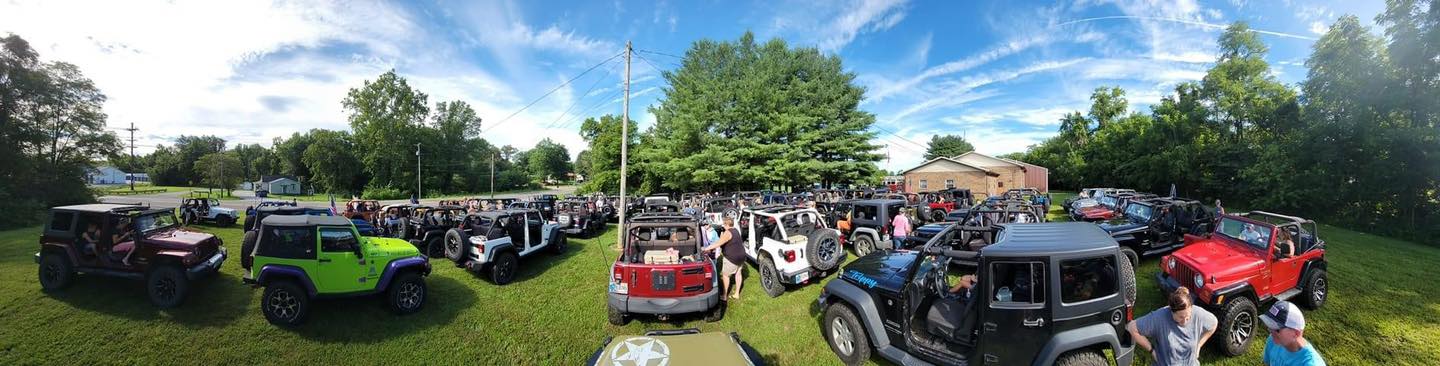 A large group of cars are parked in a grassy field.