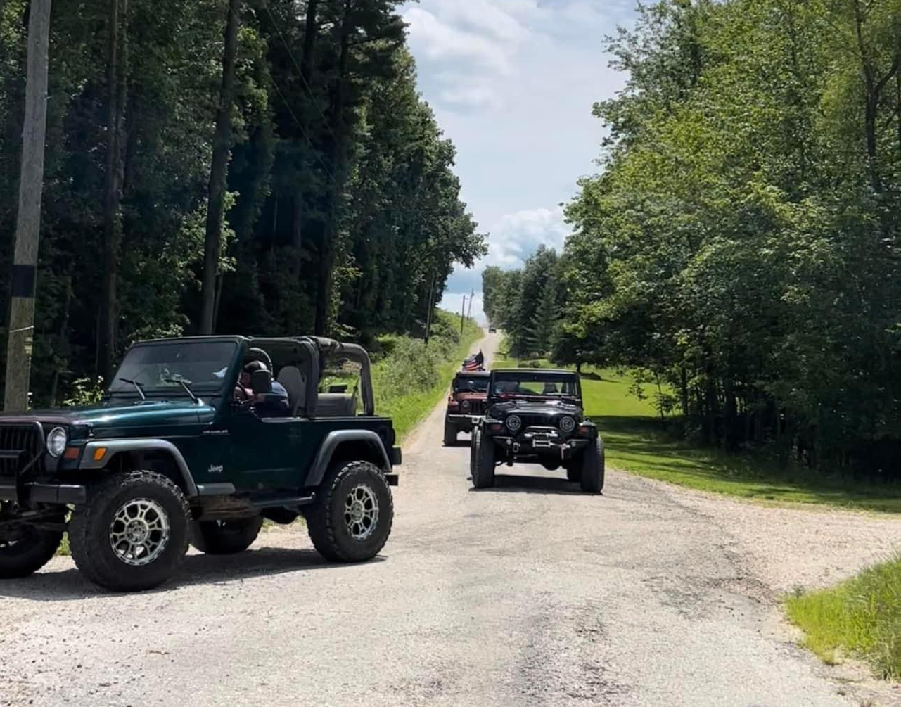 A group of jeeps are driving down a dirt road