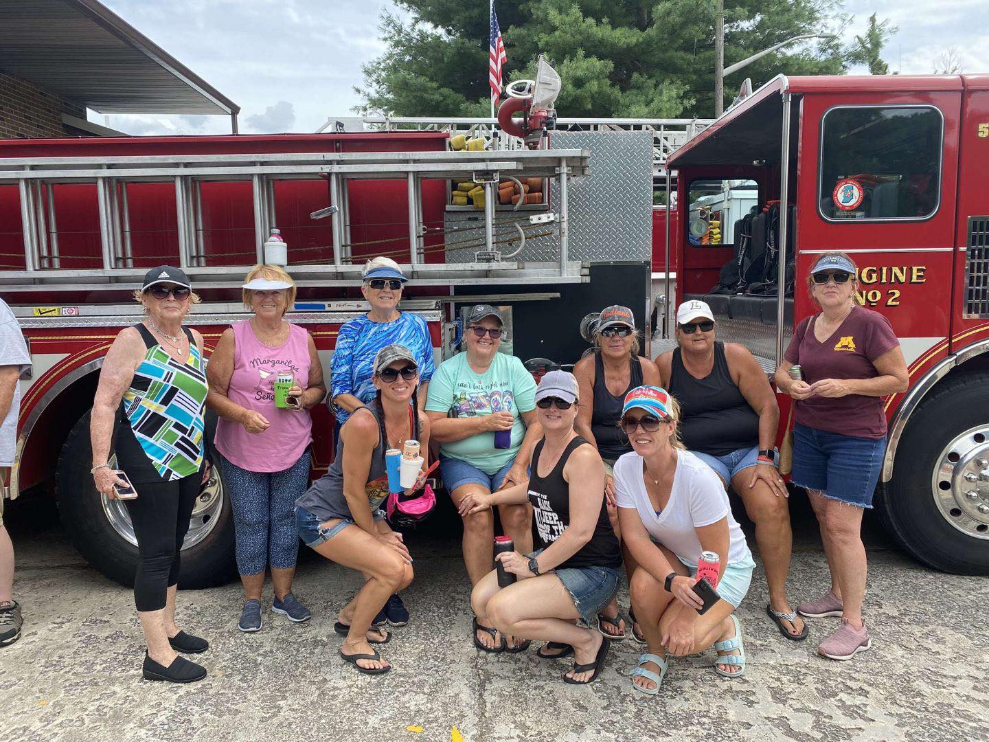 A group of women are posing for a picture in front of a fire truck.