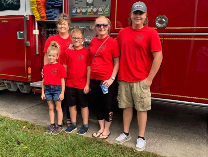 A family is standing in front of a red fire truck.