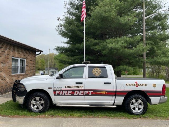 A white truck with the word fire dept on the side is parked in front of a brick building.