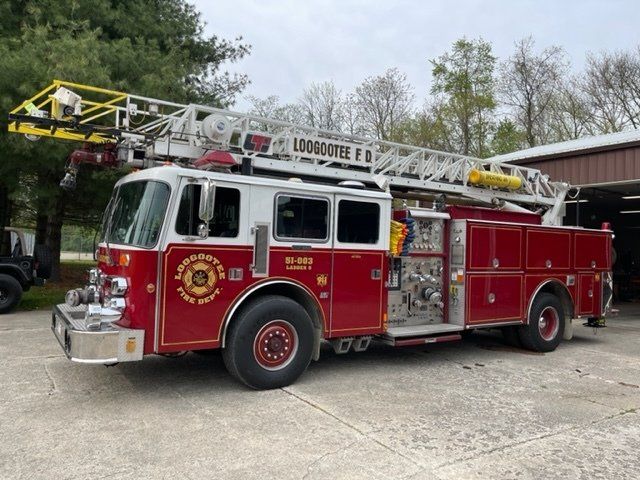 A red fire truck with a yellow ladder is parked in front of a building.