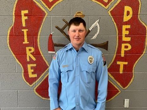 A man standing in front of a fire department logo