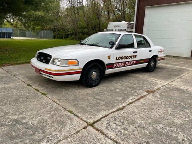 A white fire department car is parked in front of a garage.