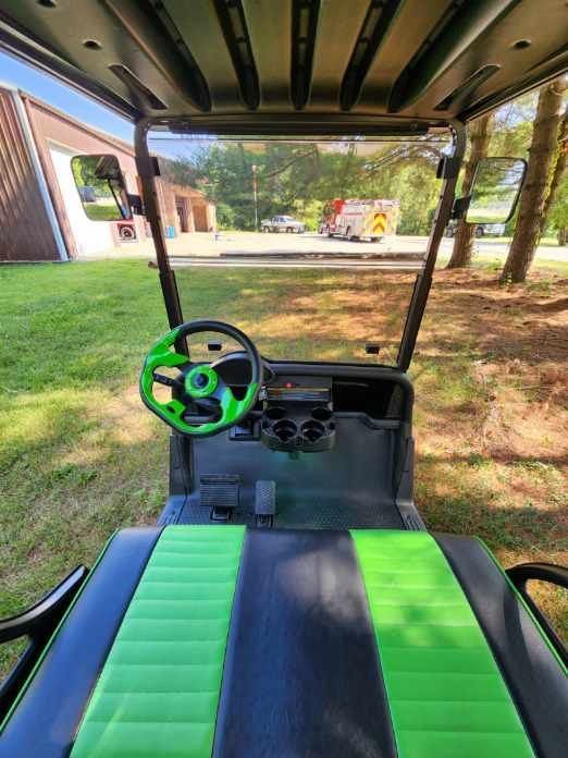 The inside of a golf cart with green seats and a green steering wheel.