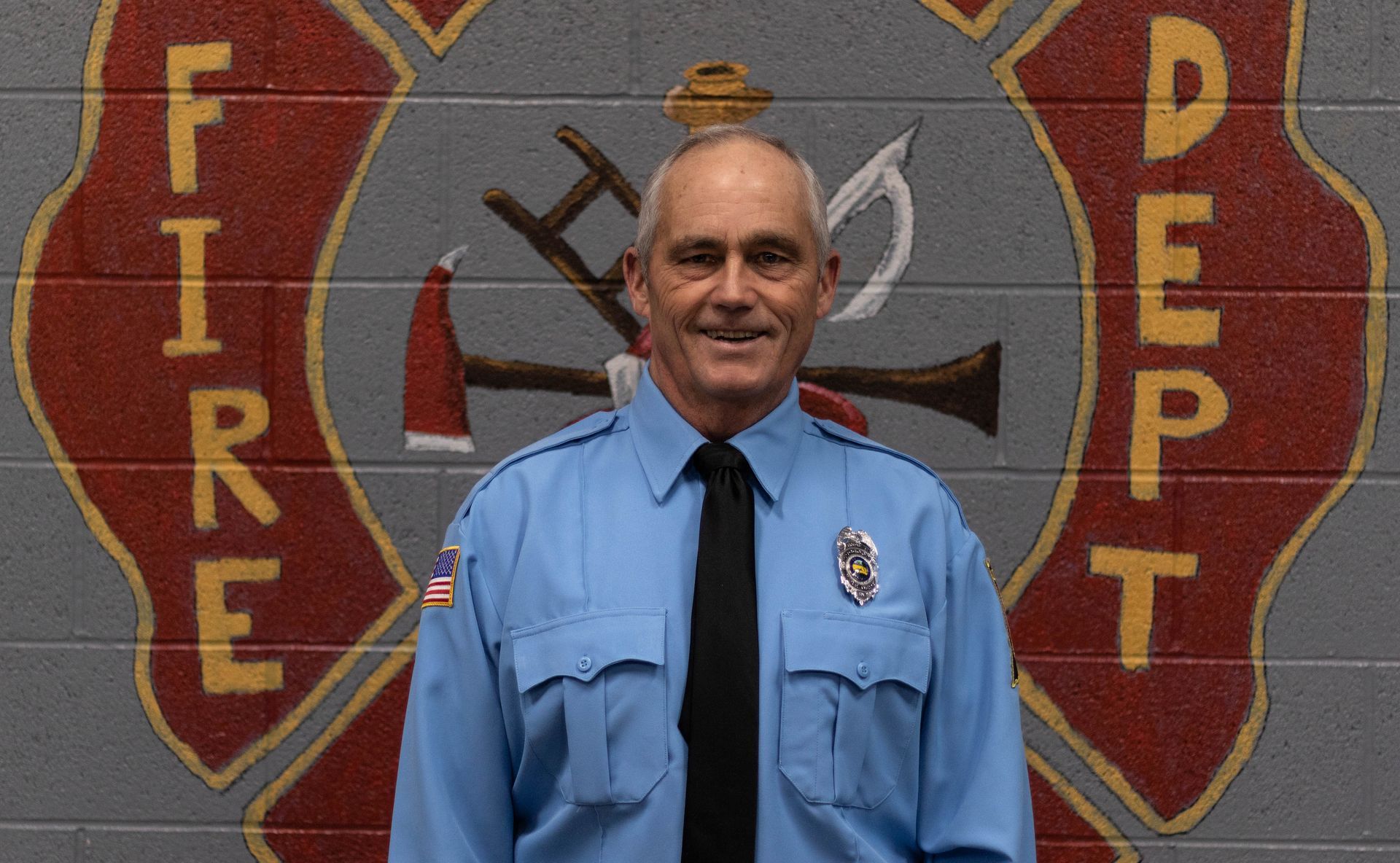 A man is standing in front of a fire department logo