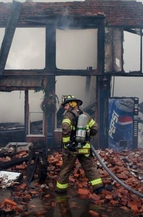 A fireman is standing in front of a pepsi can