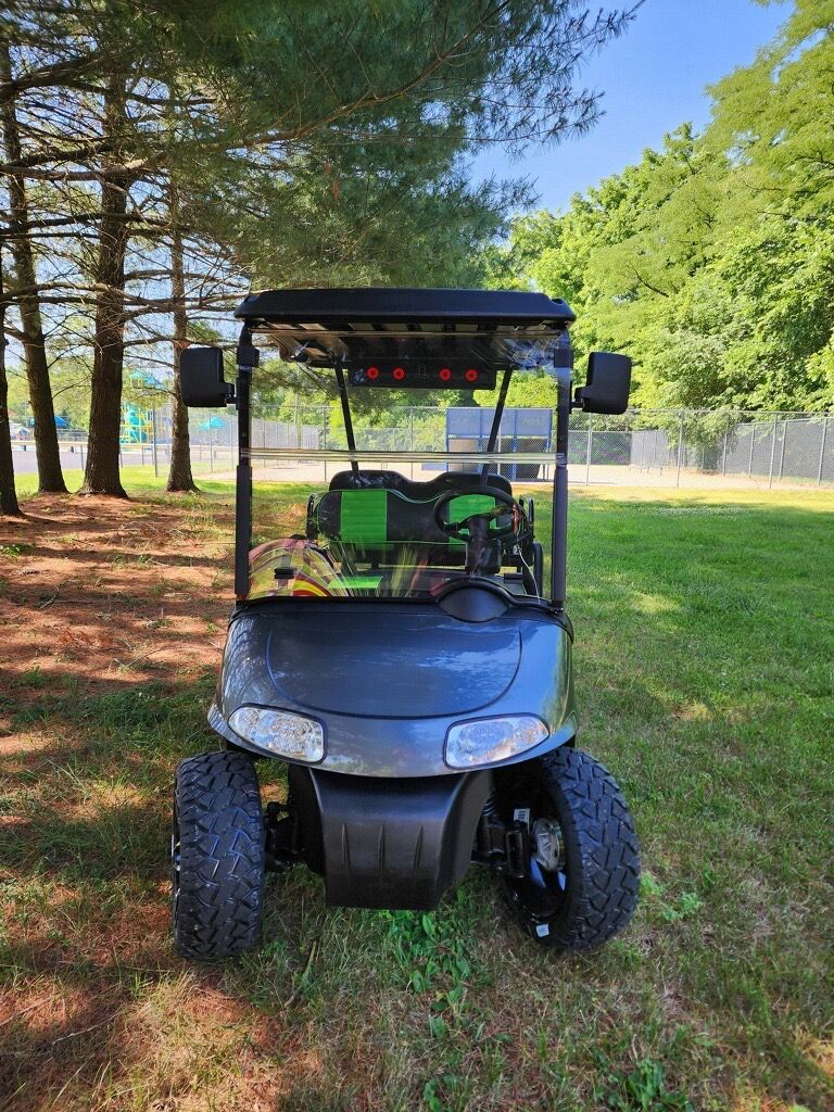 A black golf cart is parked in a grassy field.