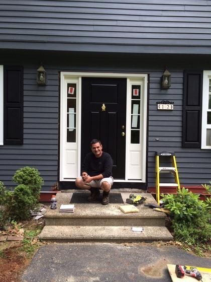 A man is kneeling in front of a blue house