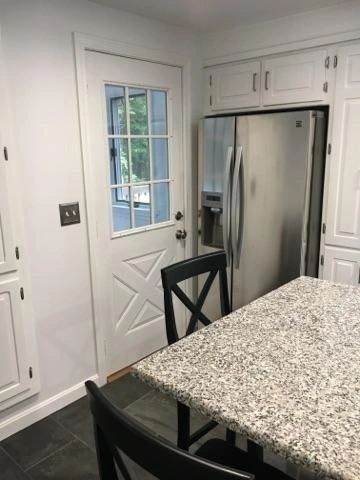 A kitchen with a table and chairs and a refrigerator.