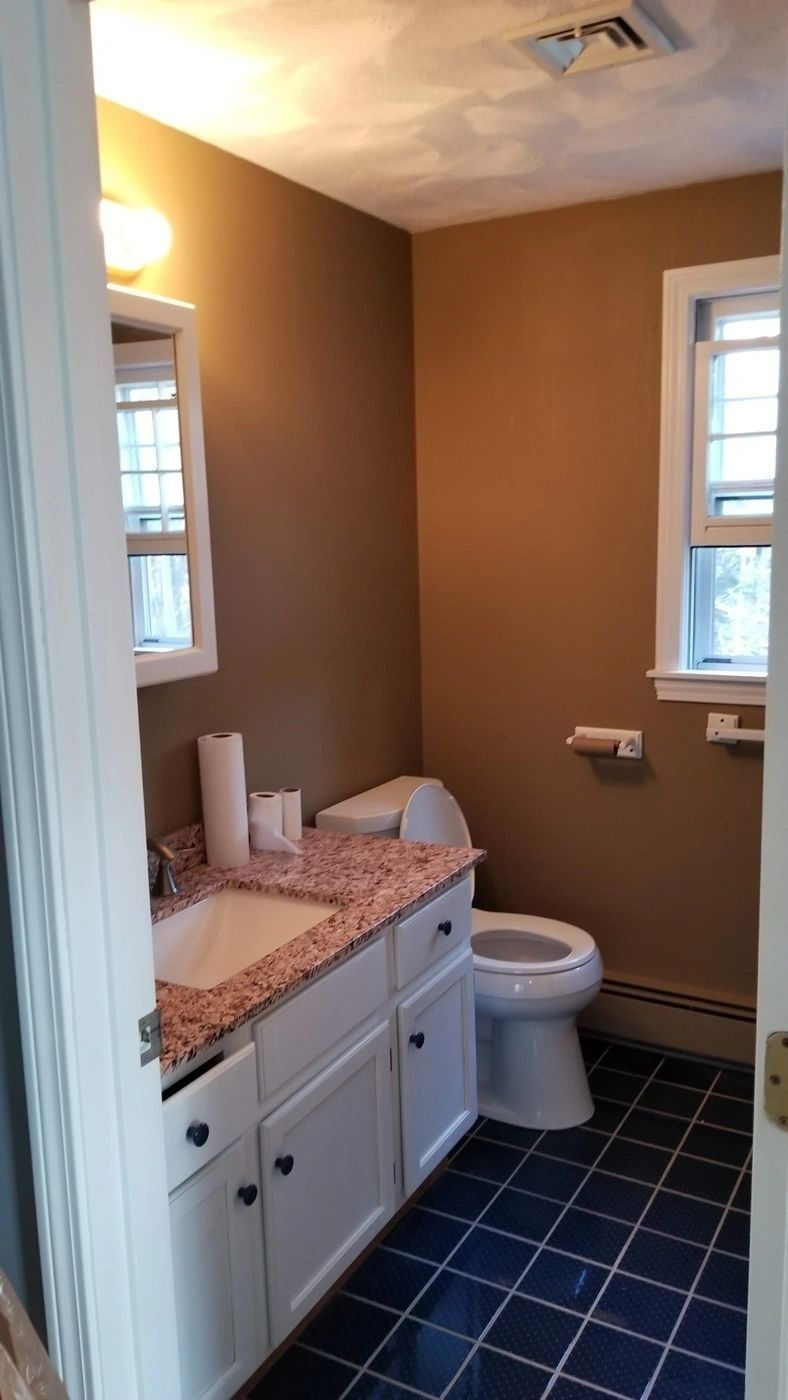 A bathroom with a sink , toilet , and window.