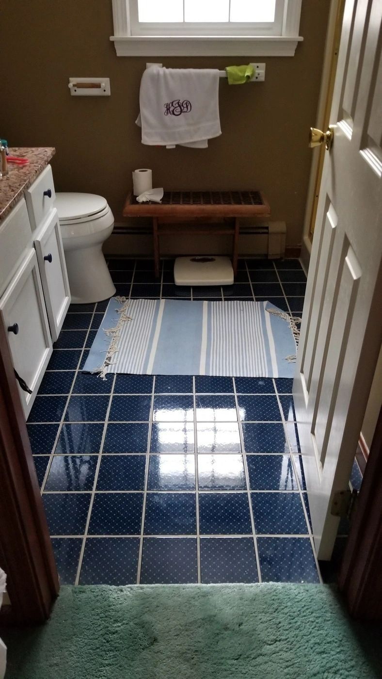 A bathroom with a blue tile floor and a white toilet.