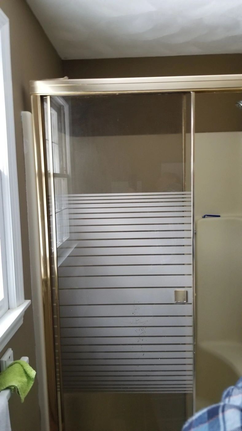 A shower stall with a striped glass door in a bathroom.