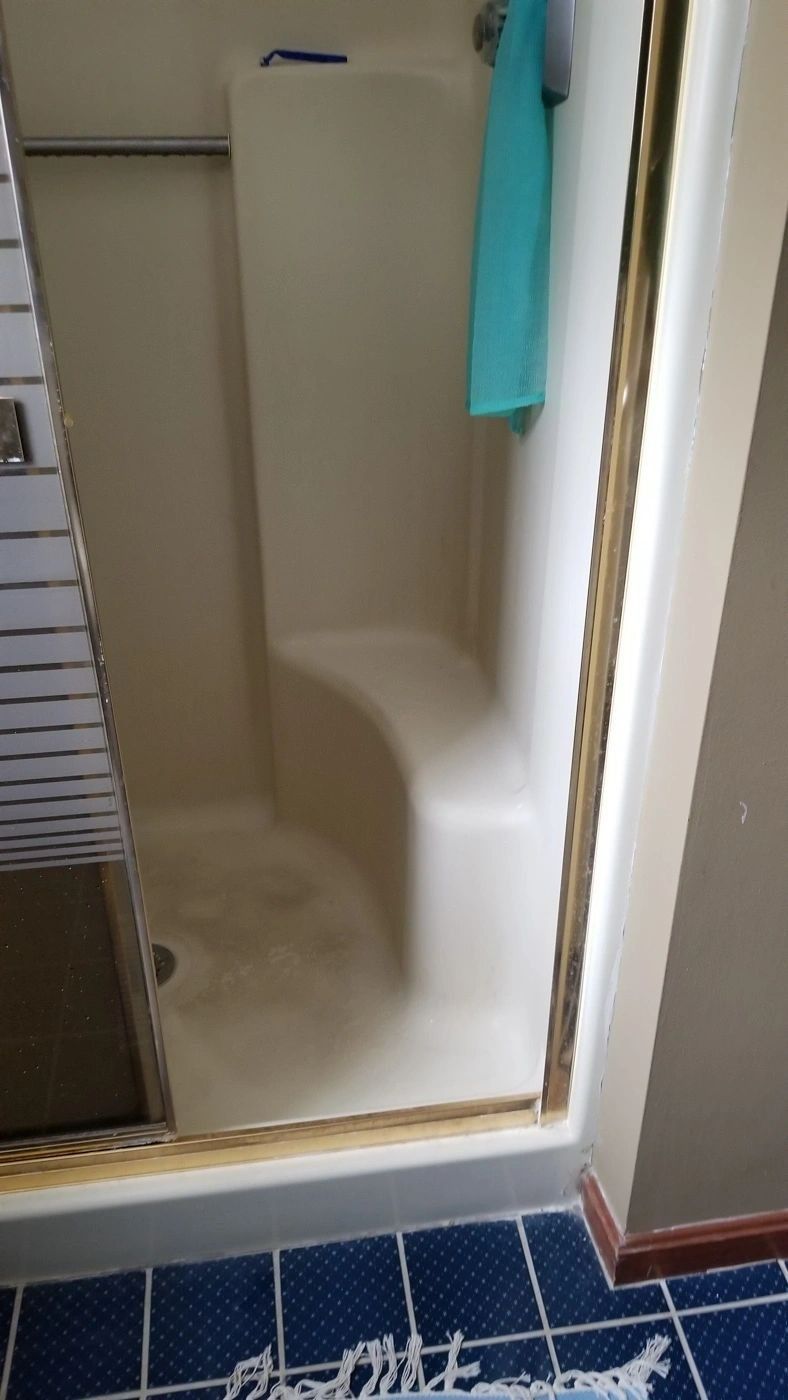 A bathroom with a shower stall and a blue towel hanging on the wall.