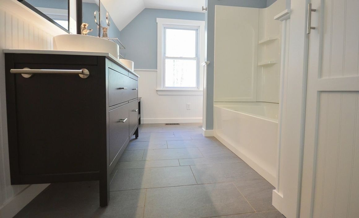A bathroom with a sink , tub , mirror and window.