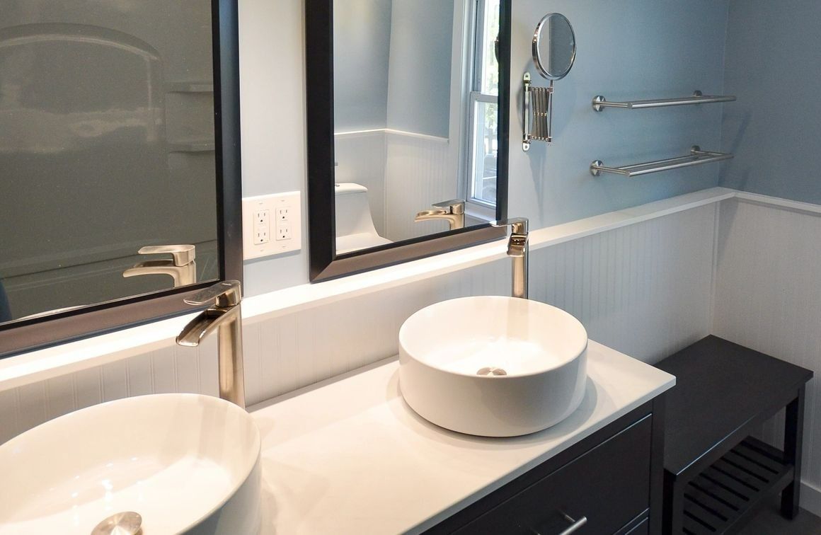 A bathroom with two sinks , a mirror and a bench.