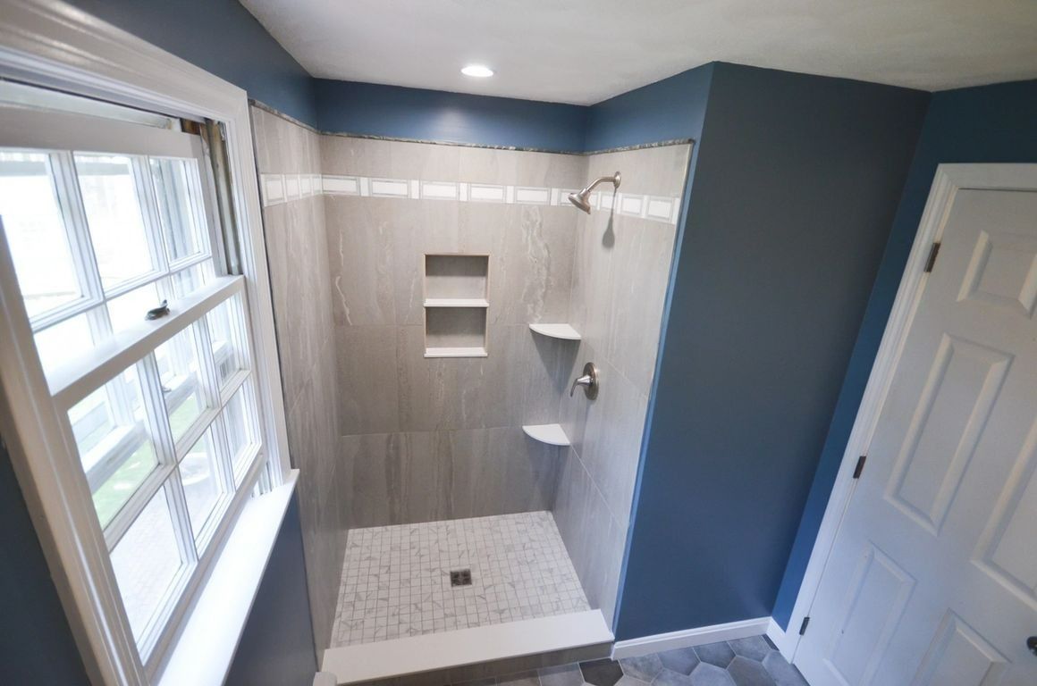 A bathroom with a walk in shower and a window