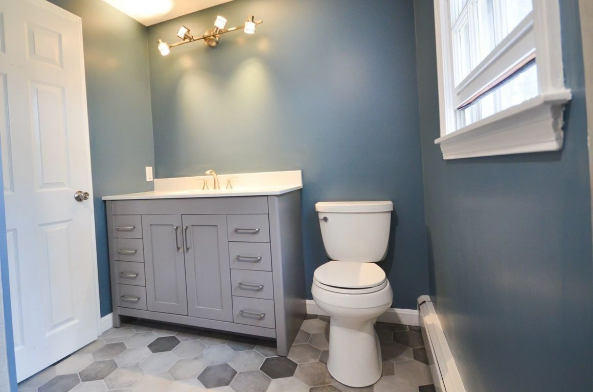 A bathroom with a toilet , sink , and window.