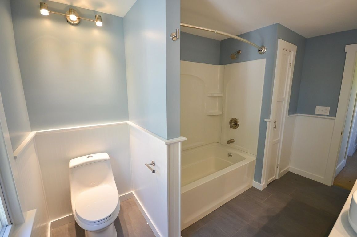 A bathroom with a toilet , tub and shower.
