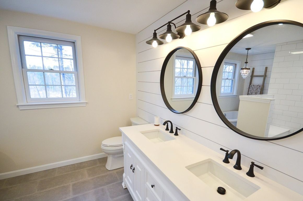 A bathroom with two sinks , a toilet and two mirrors.