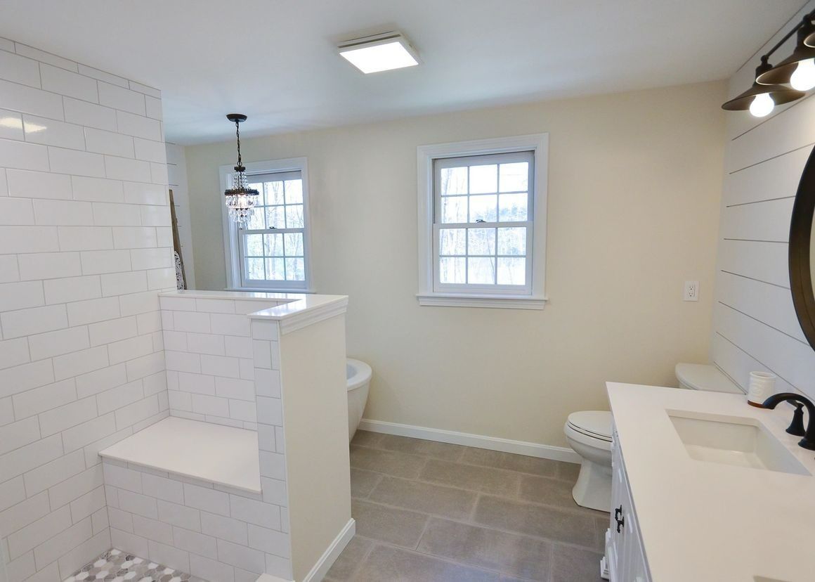 A bathroom with a toilet a sink and a mirror