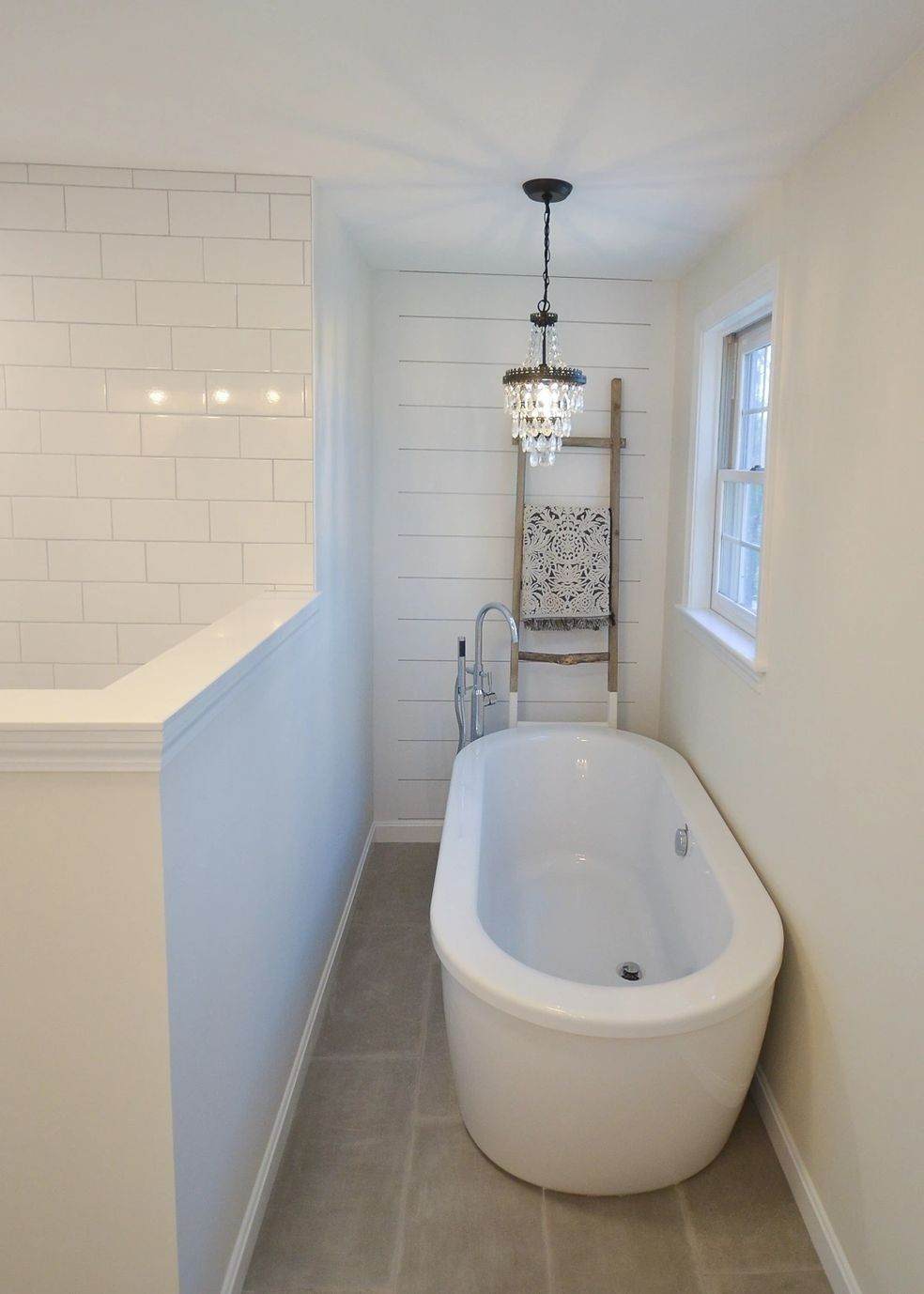A bathtub in a bathroom next to a window