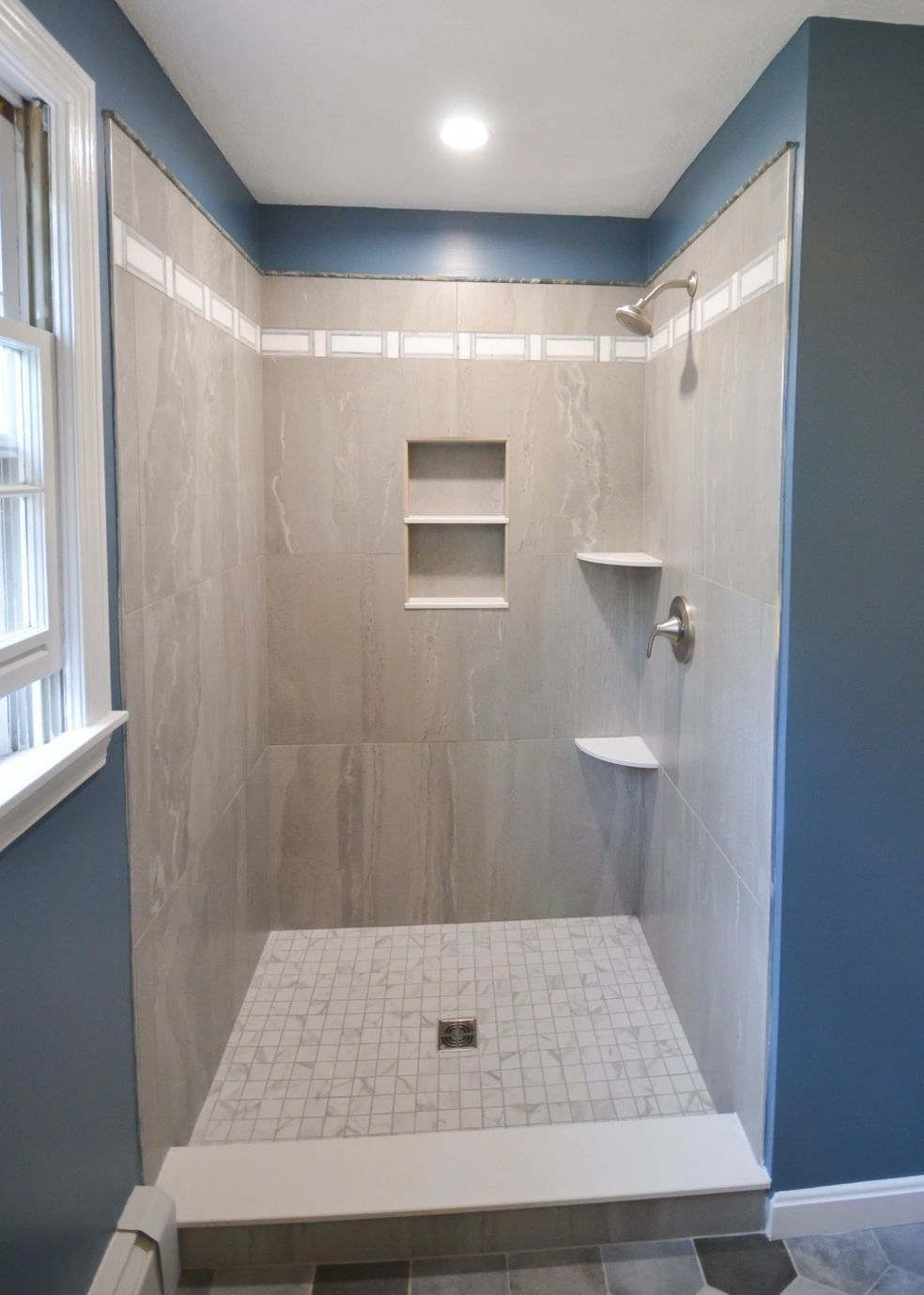 A bathroom with a walk in shower and a window.