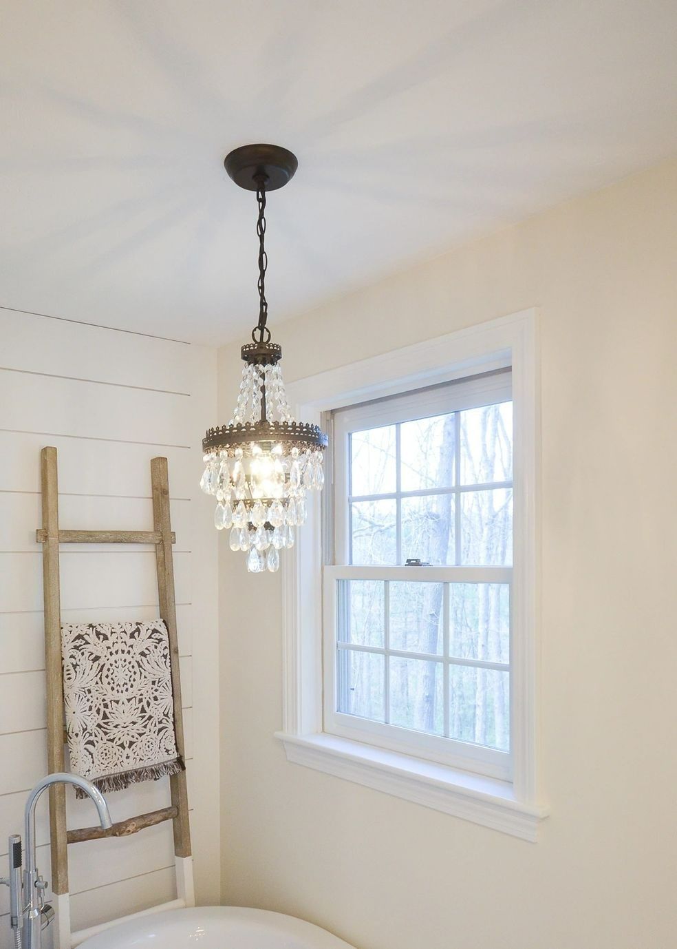 A bathroom with a bathtub and a chandelier hanging from the ceiling.