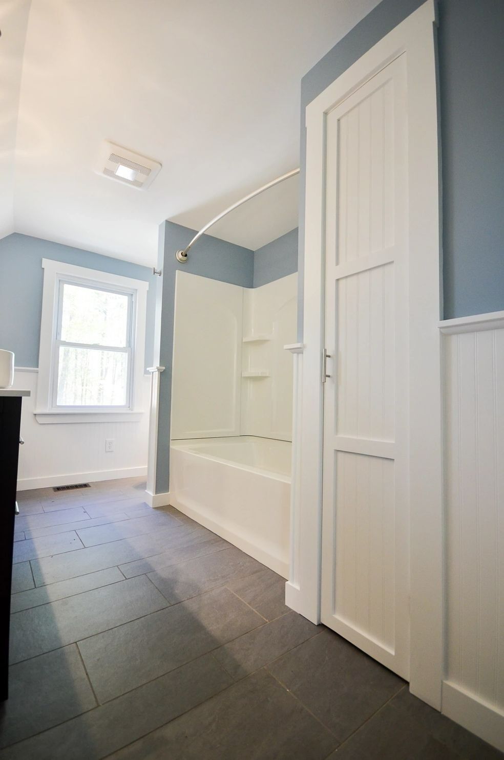 A bathroom with a tub , shower , sink and window.