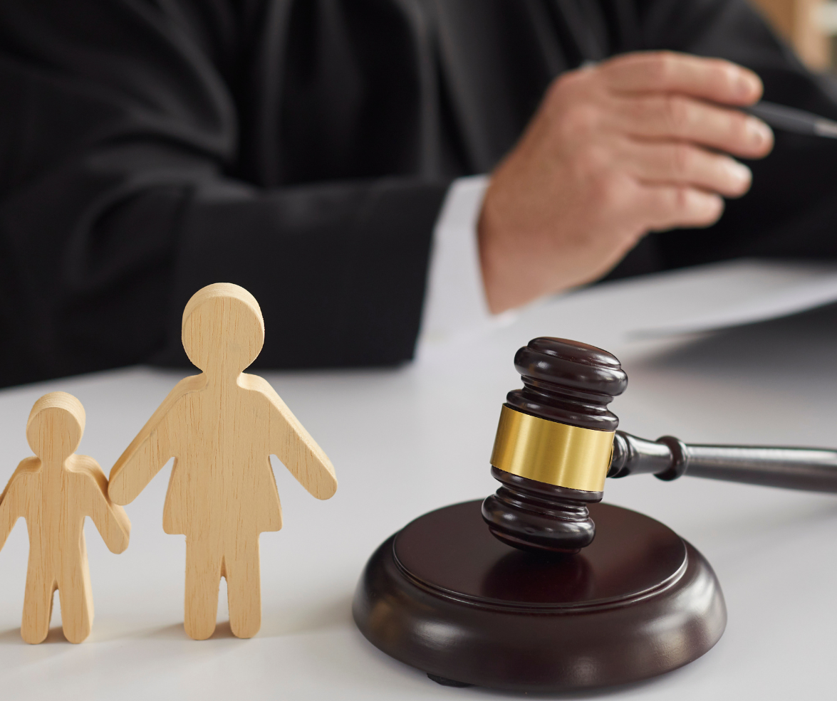 Judge with gavel and family figurines on a table; legal concept.