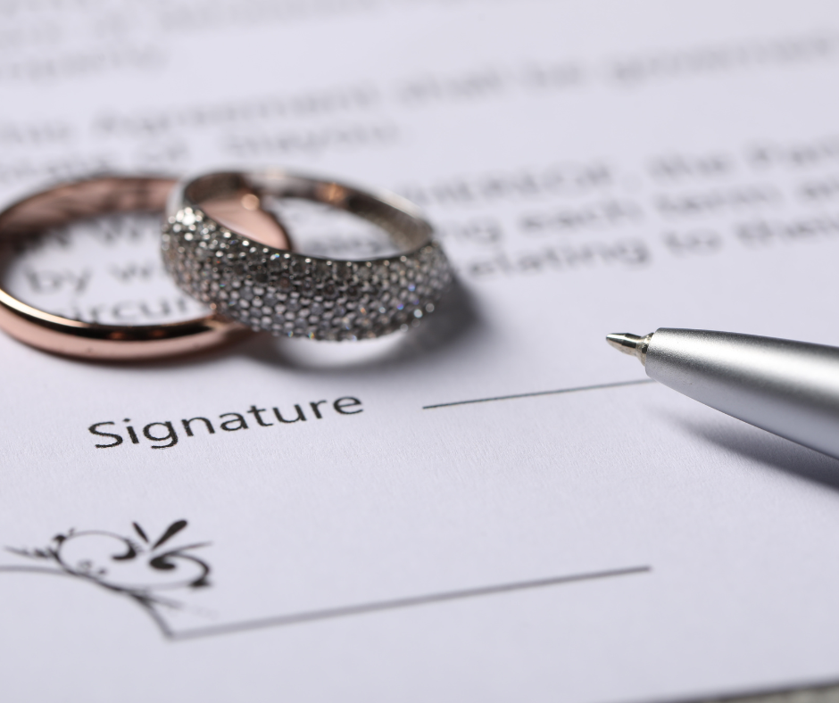 Close-up of two wedding rings on a document labeled “Signature” with a pen