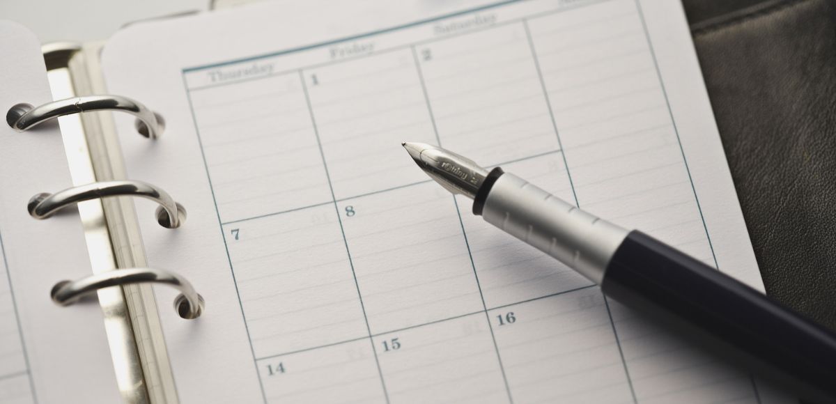 Calendar planner with a pen resting on the open page to build a custody schedule