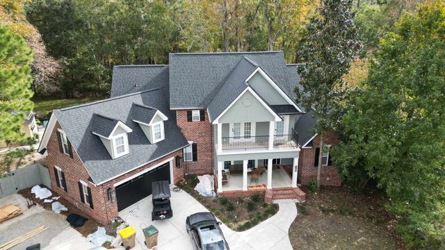 Two-story brick house with a dark gray roof, a two-car garage, and a porch.