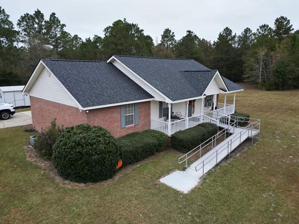 Brick and white house with porch and wheelchair ramp on a grassy lawn.