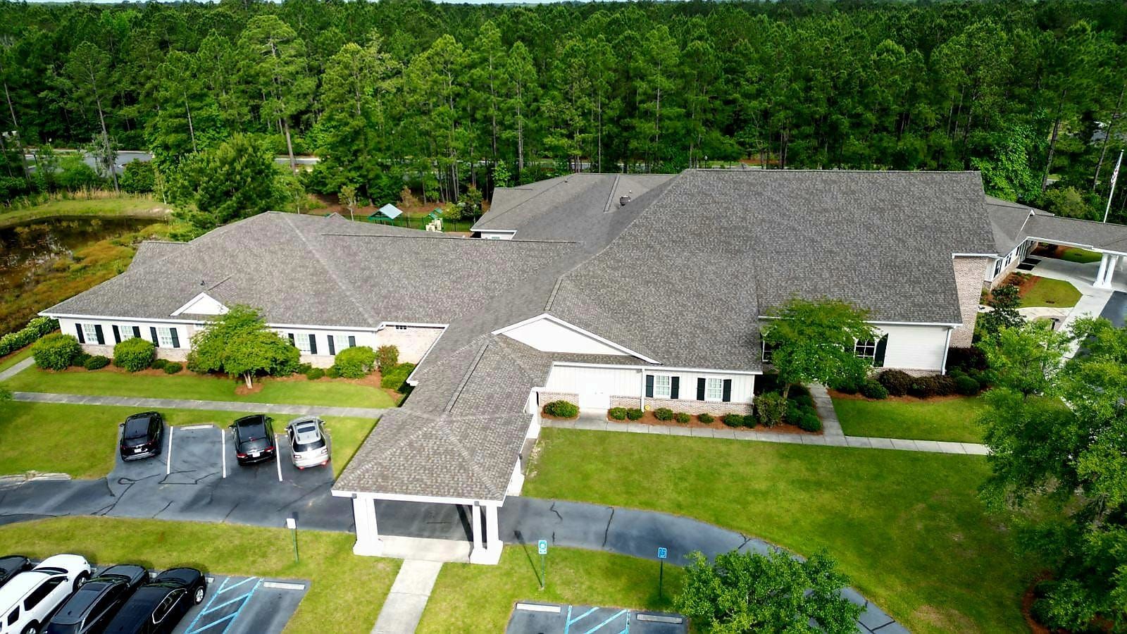 A large, light-colored building with a gray roof and numerous windows.