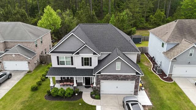 Overhead view of a house with a dark gray shingled roof, set on a green grassy lot.